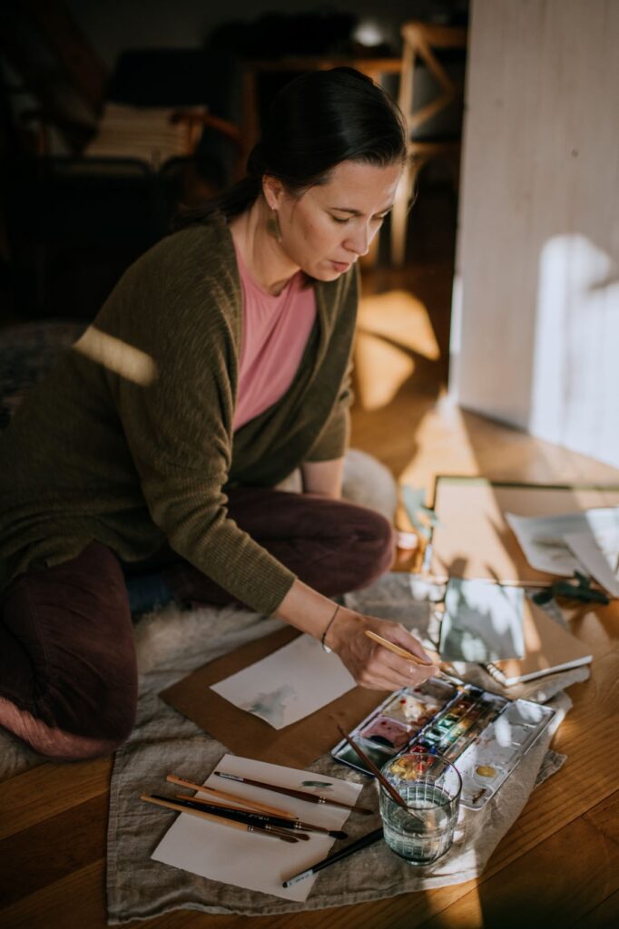 An artist painting with watercolor in her home studio